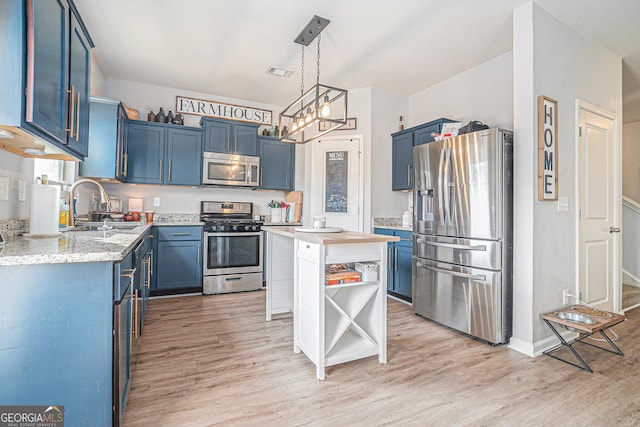 kitchen with hanging light fixtures, light wood-type flooring, stainless steel appliances, and blue cabinets