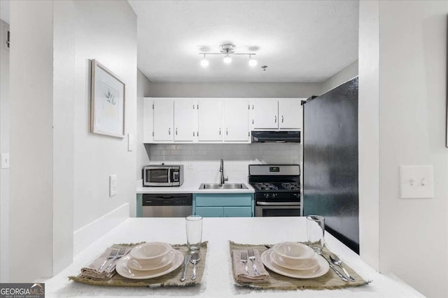 kitchen featuring appliances with stainless steel finishes, tasteful backsplash, sink, exhaust hood, and white cabinetry