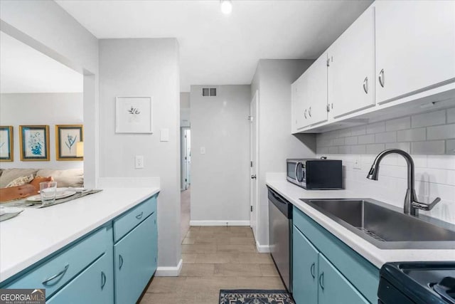 kitchen featuring dishwasher, blue cabinets, sink, tasteful backsplash, and white cabinetry