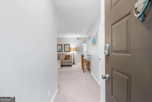 corridor with light colored carpet and a textured ceiling