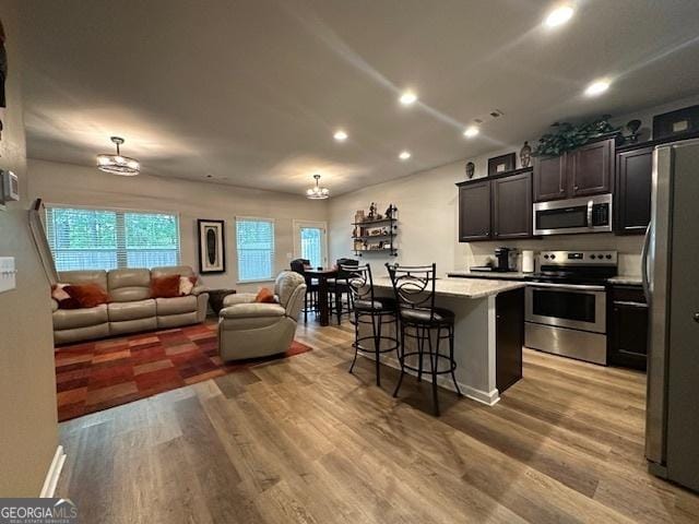 kitchen featuring appliances with stainless steel finishes, light wood-type flooring, a kitchen island, and a kitchen breakfast bar