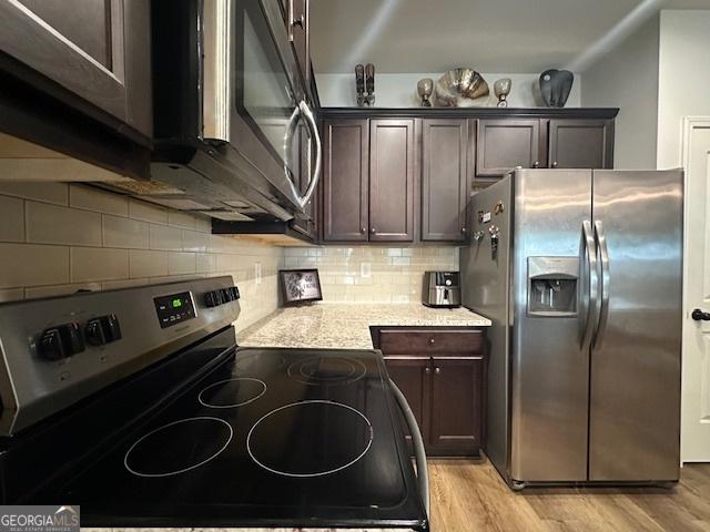 kitchen featuring backsplash, light hardwood / wood-style flooring, light stone countertops, dark brown cabinetry, and stainless steel appliances