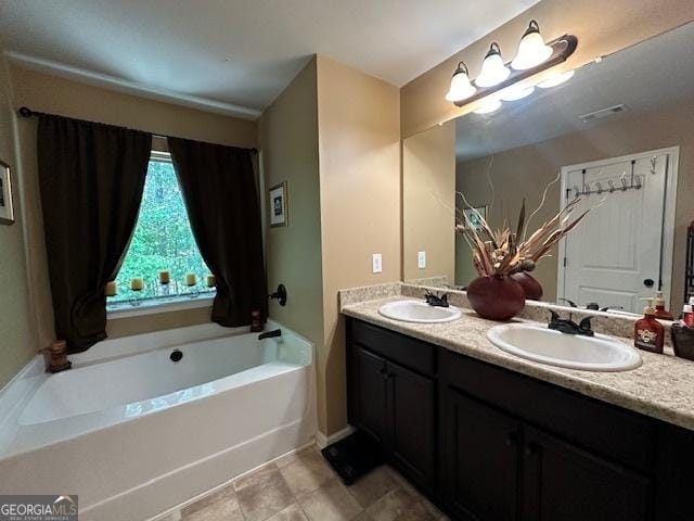 bathroom with a bath, vanity, and tile patterned floors