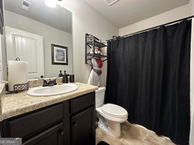 bathroom featuring toilet, vanity, tile patterned floors, and a shower with shower curtain