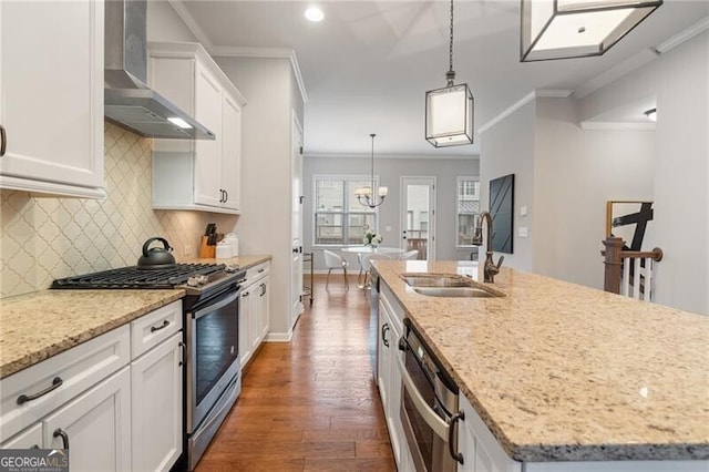 kitchen featuring wall chimney exhaust hood, sink, dishwasher, stainless steel gas stove, and an island with sink