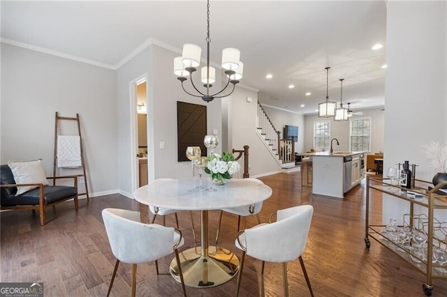 dining area with dark wood-type flooring, a notable chandelier, ornamental molding, and sink