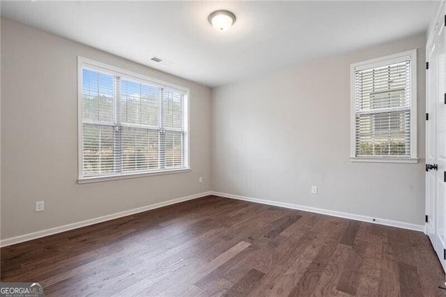 empty room featuring a wealth of natural light and dark hardwood / wood-style floors