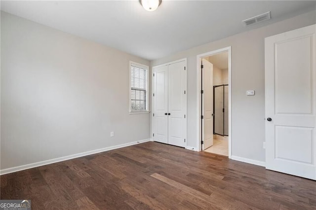 unfurnished bedroom with dark wood-type flooring and a closet