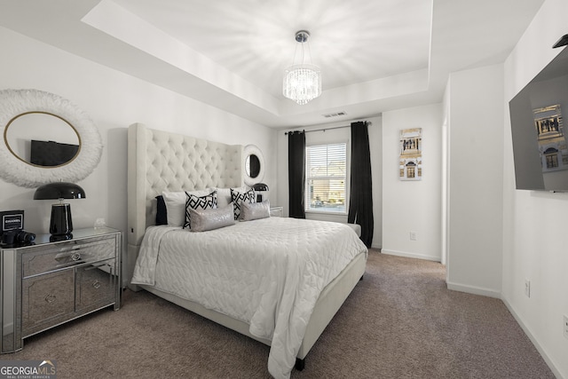 carpeted bedroom with an inviting chandelier and a raised ceiling