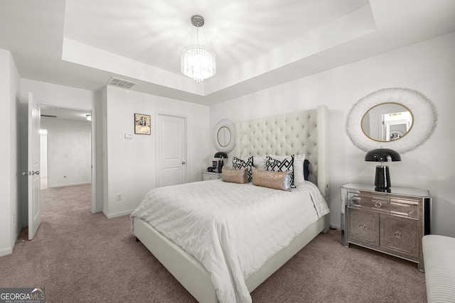 carpeted bedroom with a tray ceiling and a notable chandelier