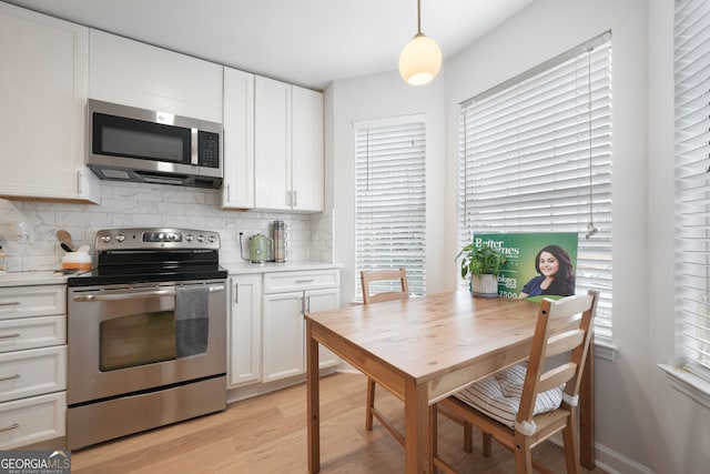 kitchen featuring pendant lighting, decorative backsplash, white cabinetry, and stainless steel appliances