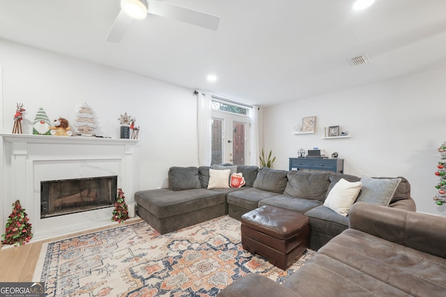 living room featuring ceiling fan, wood-type flooring, a premium fireplace, and french doors