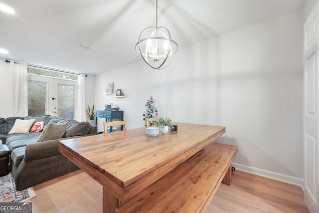 dining space featuring a chandelier, light wood-type flooring, and french doors