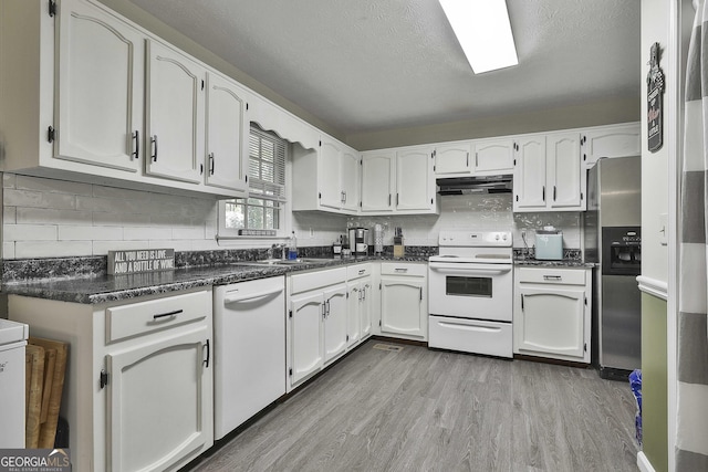 kitchen featuring white appliances, decorative backsplash, light wood-style flooring, under cabinet range hood, and a sink