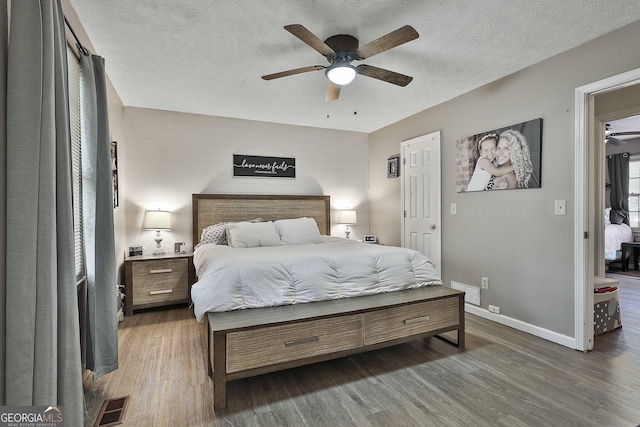 bedroom with baseboards, visible vents, dark wood finished floors, and a textured ceiling