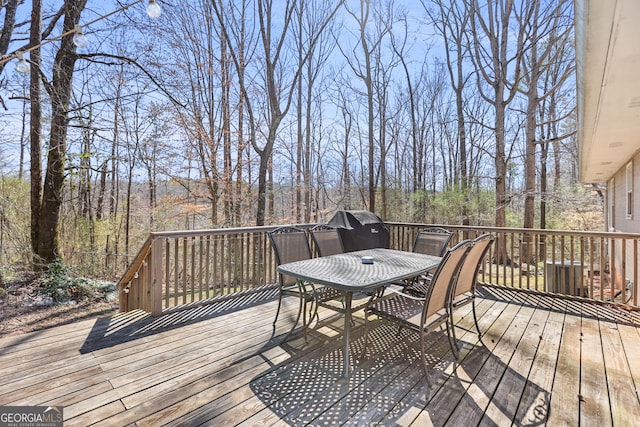 deck featuring outdoor dining space and a forest view