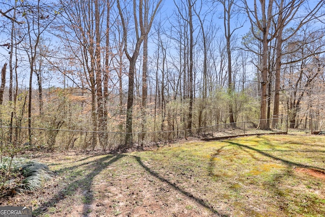 view of yard with a forest view and fence