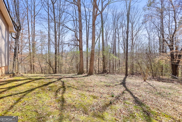 view of yard featuring fence and a wooded view