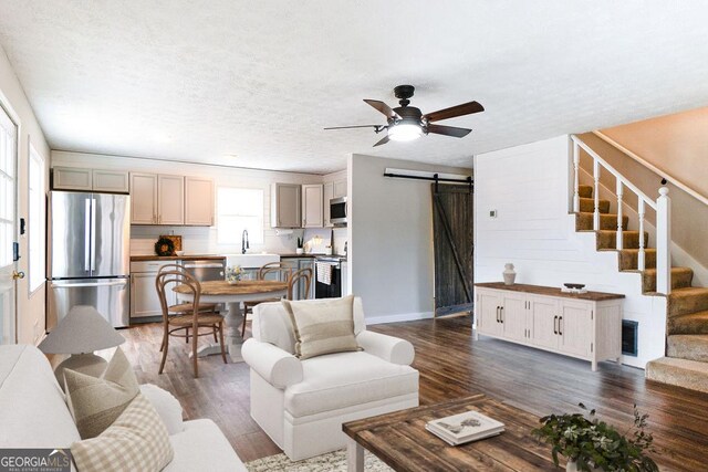 living room featuring a barn door, dark hardwood / wood-style floors, a healthy amount of sunlight, and a textured ceiling