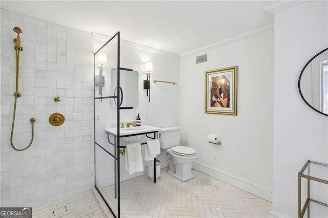 bathroom featuring a tile shower, crown molding, and toilet