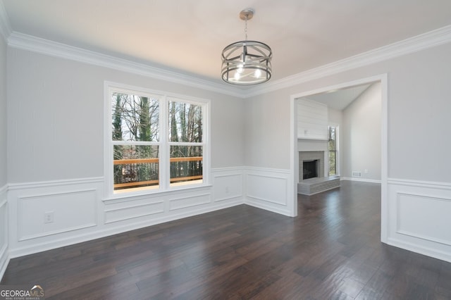 unfurnished living room featuring a brick fireplace, crown molding, dark hardwood / wood-style flooring, and an inviting chandelier