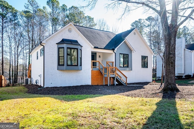 view of front of home with a front yard and central AC unit