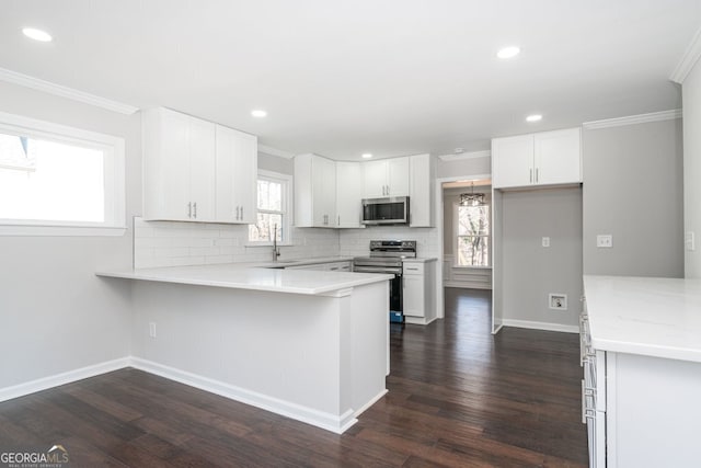 kitchen featuring white cabinets, dark hardwood / wood-style floors, kitchen peninsula, and appliances with stainless steel finishes