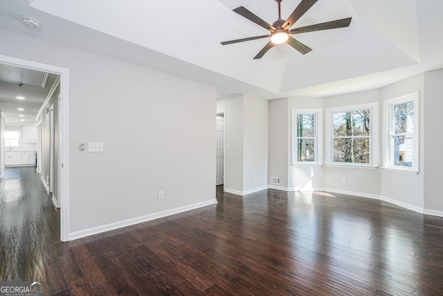 empty room featuring a tray ceiling, ceiling fan, and dark hardwood / wood-style floors