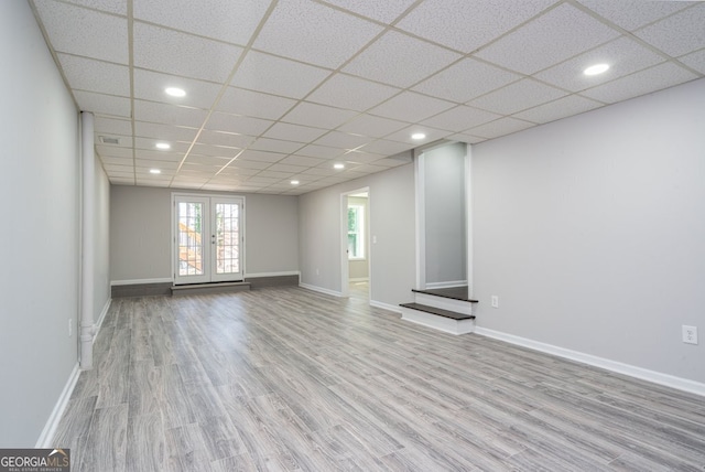 empty room with french doors, a paneled ceiling, and light hardwood / wood-style flooring