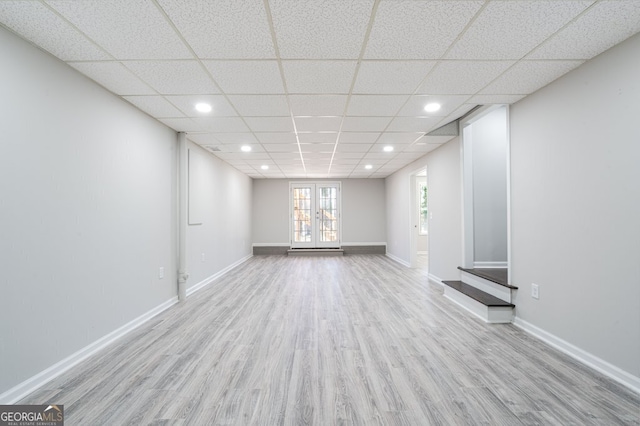 interior space featuring a drop ceiling, light wood-type flooring, and french doors