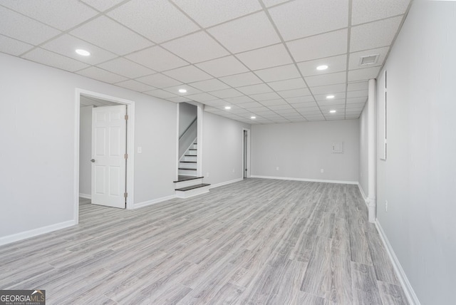 basement with a paneled ceiling and light wood-type flooring