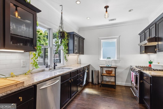 kitchen with decorative light fixtures, sink, ornamental molding, and stainless steel appliances