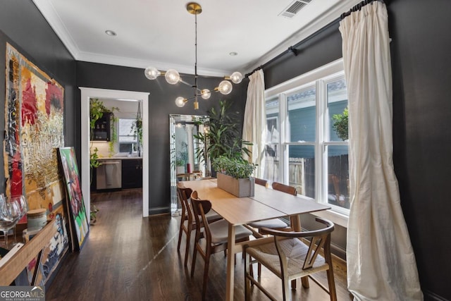 dining area featuring dark hardwood / wood-style flooring, an inviting chandelier, and crown molding