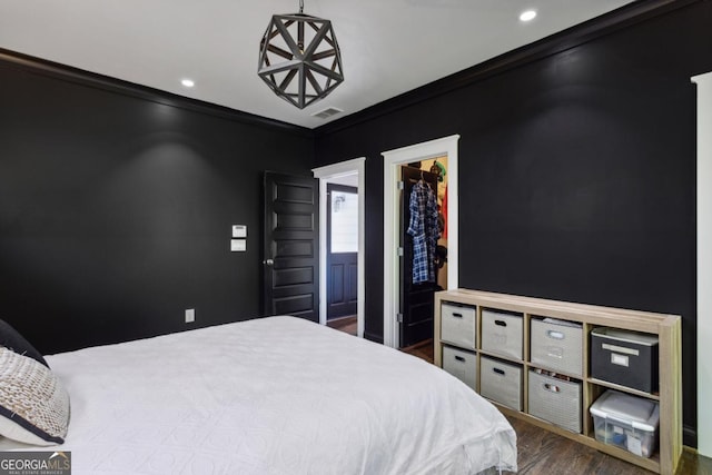 bedroom featuring wood-type flooring, a walk in closet, ensuite bath, and crown molding