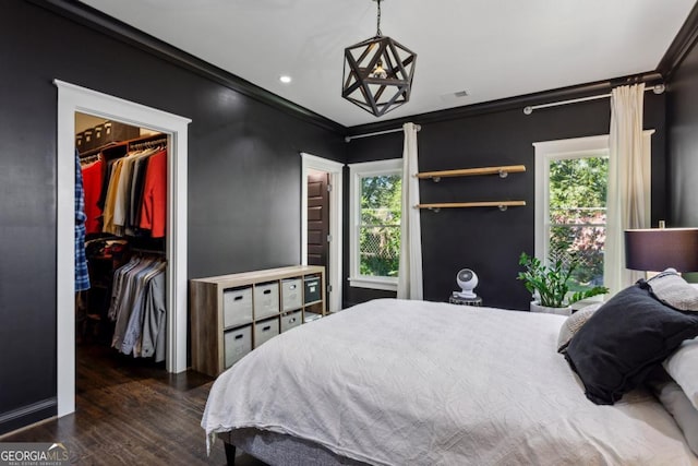 bedroom featuring multiple windows, a spacious closet, a closet, and ornamental molding