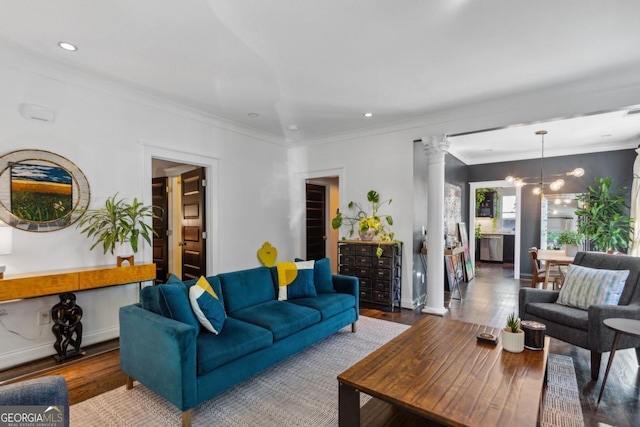 living room featuring ornate columns, hardwood / wood-style flooring, a notable chandelier, and ornamental molding