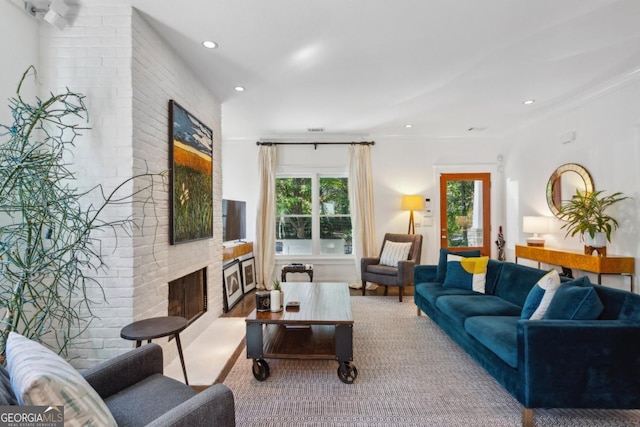 living room featuring ornamental molding, a fireplace, and light hardwood / wood-style flooring