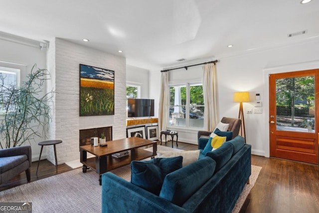 living room with dark wood-type flooring and a brick fireplace