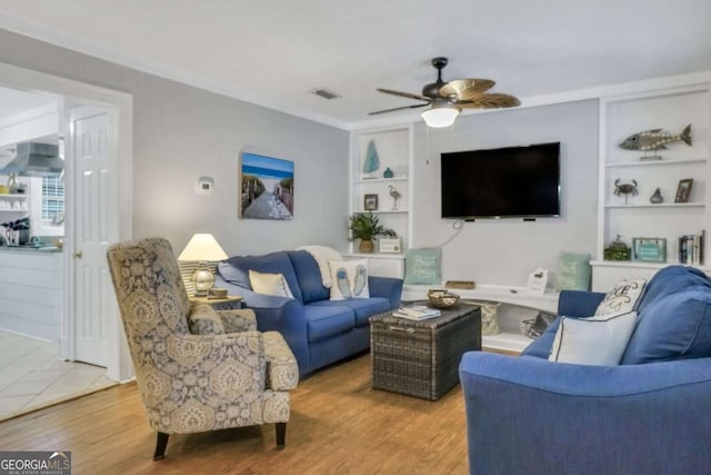 living room featuring ceiling fan, built in features, hardwood / wood-style floors, and ornamental molding