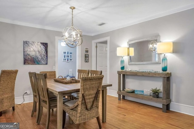 dining area with ornamental molding, a chandelier, and hardwood / wood-style flooring