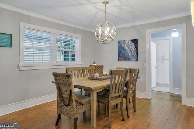 dining space with a notable chandelier, wood-type flooring, and ornamental molding