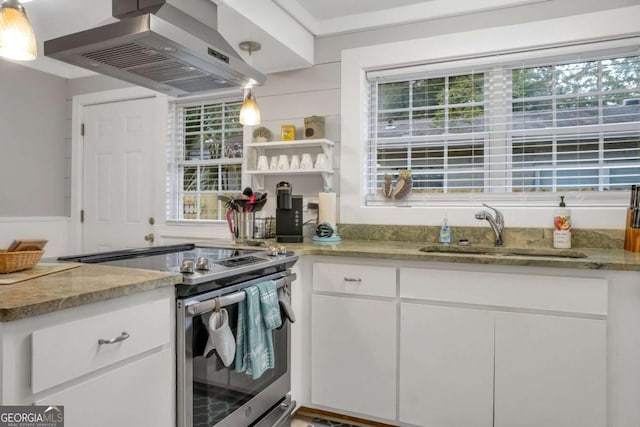 kitchen featuring stainless steel electric stove, sink, island range hood, light stone counters, and white cabinetry