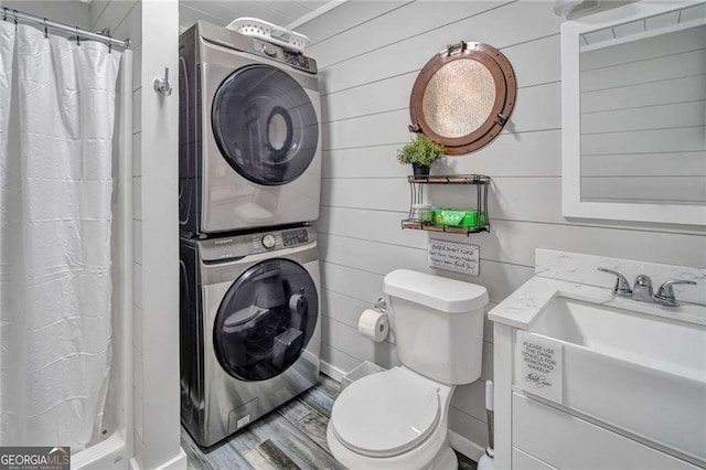 bathroom with a shower with curtain, toilet, vanity, and stacked washer and clothes dryer