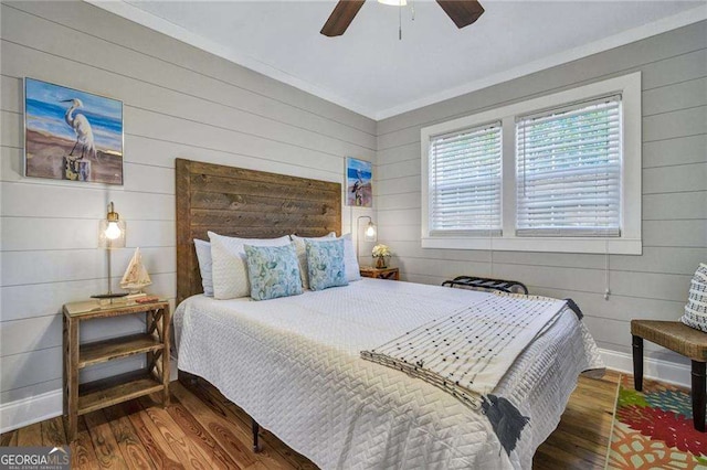 bedroom with ornamental molding, hardwood / wood-style flooring, ceiling fan, and wooden walls