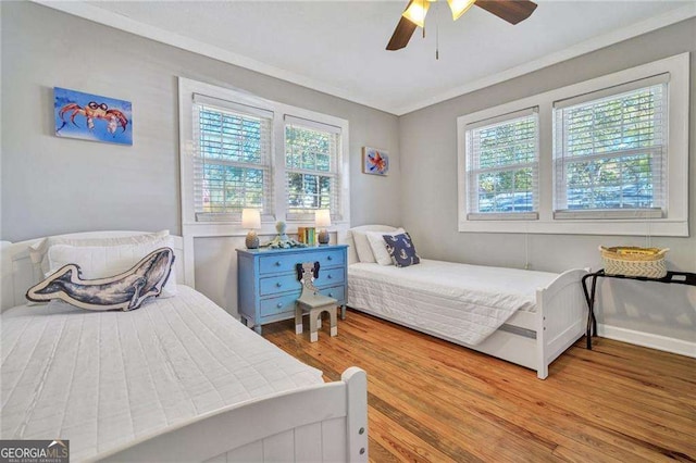 bedroom featuring multiple windows, ceiling fan, crown molding, and wood-type flooring