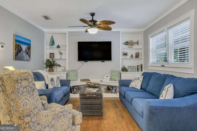 living room featuring wood-type flooring, built in features, ceiling fan, and ornamental molding