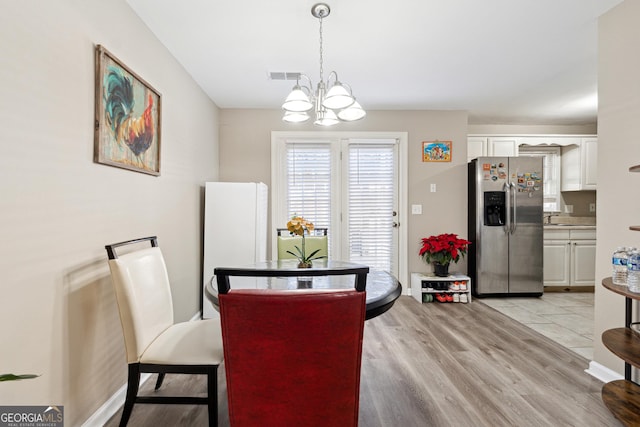 dining room with sink, light hardwood / wood-style floors, and an inviting chandelier