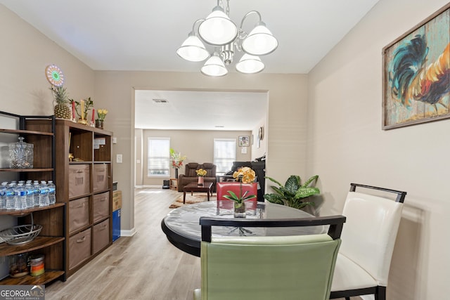 dining area with light wood-type flooring and a chandelier