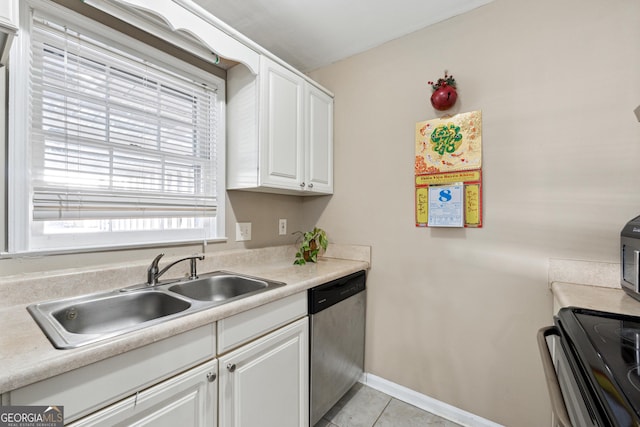 kitchen featuring stainless steel dishwasher, sink, light tile patterned floors, white cabinets, and range