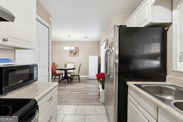 kitchen featuring stainless steel refrigerator, white cabinetry, hanging light fixtures, light tile patterned floors, and exhaust hood